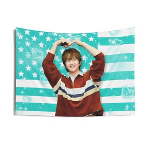 Puede incluir: Un tapiz de pared rectangular que muestra a una persona de cabello castaño con una camisa de manga larga en color granate, blanco y azul marino. El fondo tiene rayas turquesas y blancas con estrellas blancas y corazones azules.
