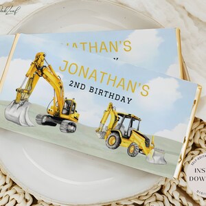 May include: A printable chocolate bar wrapper featuring a yellow excavator with a blue sky background. The text on the wrapper reads "Jonathan's 2nd Birthday".