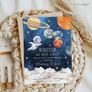 May include: Blue baby shower invitation with a watercolor illustration of an astronaut holding balloons shaped like planets. The text reads "Houston, We Have a Boy" and includes the name "Madison Roberts".