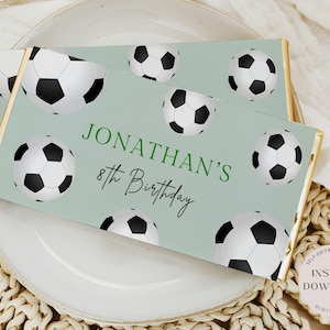 Op de afbeelding: Een groene en witte bedrukbare chocolade-reepverpakking met een voetbalthema. De verpakking zegt "Jonathan's 8th Birthday".
