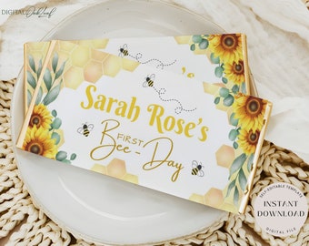 May include: A printable, yellow and white first day of school sign with a bee theme. The sign says "Sarah Rose's First Bee Day" and features a honeycomb pattern, bees, and sunflowers.