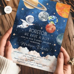 May include: A blue and white baby shower invitation with a cartoon astronaut holding planets. The text reads "Houston, We Have A Boy" and includes the date, time, and RSVP information.