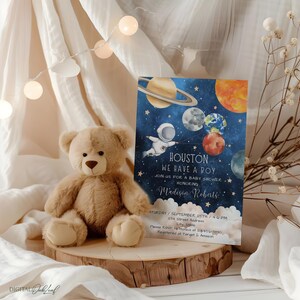 May include: A blue and white baby shower invitation with a watercolor illustration of an astronaut holding balloons shaped like planets. The text reads "Houston, We Have a Boy" and includes the name "Madison Roberts".