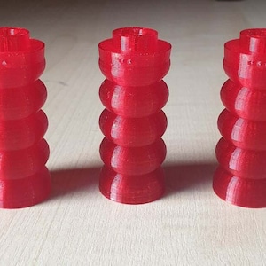 May include: Three red, 3D printed, flexible, cylindrical objects with a textured surface. Each object has a rounded top and bottom.