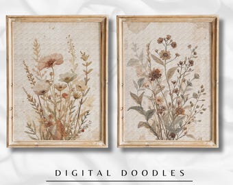 May include: Two framed floral art prints. Each print features watercolor illustrations of wildflowers in muted tones of beige, brown, and peach. The frames are a light gold color. The text "DIGITAL DOODLES" and "FLOWER ART" is printed below the frames.