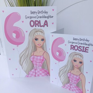 May include: Two birthday cards featuring a cartoon illustration of a girl with long blonde hair and blue eyes. The cards have the text "Happy Birthday Gorgeous Granddaughter" and the names "Orla" and "Rosie". A pink number 6 balloon is also featured.