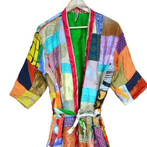 May include: A colorful patchwork robe with a green lining and a white sash. The robe is made of various fabrics with different patterns and colors, including red, blue, yellow, and green.