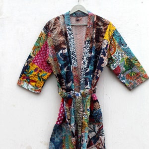 Könnte beinhalten: Eine bunte Patchwork-Robe mit floralem und geometrischem Muster. Die Robe hat einen Bindegürtel und lange Ärmel.