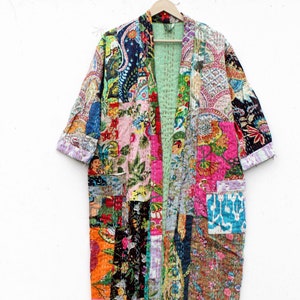 May include: A long, colorful patchwork kimono with a floral and paisley print. The kimono is made of a variety of fabrics and has a light green lining. It has a relaxed fit and is perfect for layering.