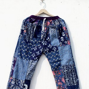Puede incluir: Pantalones de patchwork azul y morado con estampado floral. Los pantalones tienen una cintura elástica y un cordón.