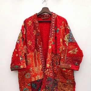 Könnte beinhalten: Eine rote gesteppte Jacke mit Patchwork-Muster und bunten Stickereien. Die Jacke hat eine lange, fließende Silhouette und eine lockere Passform.