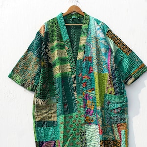 Może przedstawiać: Zielona pikowana kurtka w stylu patchwork z długim, otwartym przodem i krótkimi rękawami. Kurtka jest wykonana z różnych materiałów i ma unikalny, bohemiczny styl.