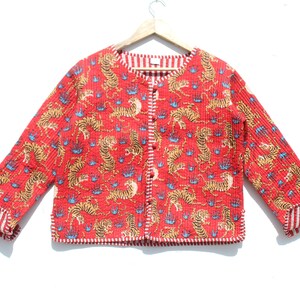 Könnte beinhalten: Eine rote gesteppte Jacke mit Tigermuster und weiß-rotem Streifenbesatz. Die Jacke hat einen Knopfverschluss und lange Ärmel.