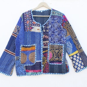 Könnte beinhalten: Eine blaue, gesteppte Jacke aus Patchwork mit Knopfleiste und zwei Taschen. Die Jacke besteht aus verschiedenen Stoffen mit unterschiedlichen Mustern, darunter Blumen-, Paisley- und geometrische Muster.
