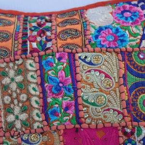 Puede incluir: Una funda de coj&iacute;n de patchwork colorido con bordados intrincados y adornos. La funda presenta una variedad de patrones florales, dise&ntilde;os de paisley y formas geom&eacute;tricas en tonos de rosa, naranja, azul, verde y dorado.