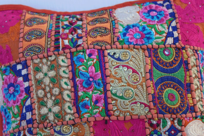Puede incluir: Una funda de coj&iacute;n de patchwork colorido con bordados intrincados y adornos. La funda presenta una variedad de patrones florales, dise&ntilde;os de paisley y formas geom&eacute;tricas en tonos de rosa, naranja, azul, verde y dorado.