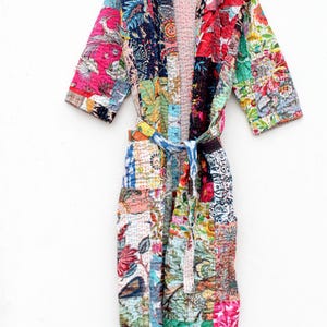 Pode incluir: Uma bata de patchwork colorida com estampa floral e cinto de laço. A bata é feita de algodão e tem uma textura acolchoada.