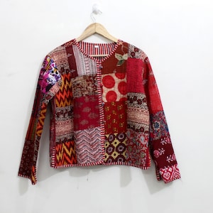 Könnte beinhalten: Eine rote, orange und blaue Patchworkjacke mit Knopfleiste. Die Jacke ist aus gestepptem Stoff und hat lange Ärmel.