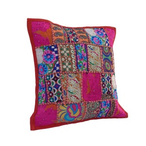 Könnte beinhalten: Ein rosafarbenes und rotes Patchwork-Kissenbezug mit bunten Stickereien und Pailletten. Der Kissenbezug besteht aus verschiedenen Stoffen und hat einen einzigartigen, bohemischen Stil.