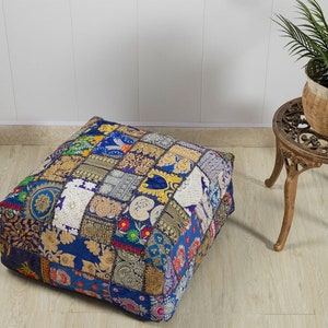 Puede incluir: Un cojín de suelo de patchwork azul y dorado con intrincados detalles de bordado. El cojín está hecho de una variedad de telas y es perfecto para agregar un toque de estilo bohemio a cualquier habitación.