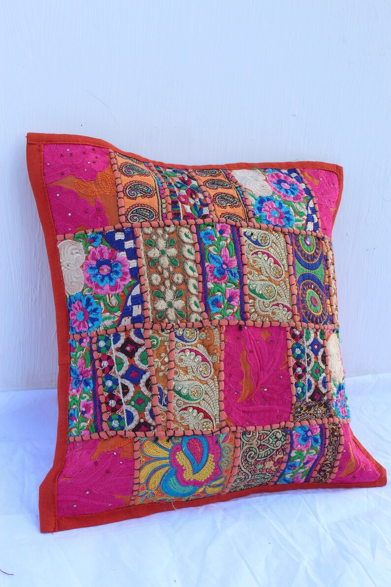 Puede incluir: Una funda de coj&iacute;n de patchwork colorido con bordados intrincados y lentejuelas. La funda est&aacute; hecha de varias telas en tonos de rosa, naranja, azul, verde y dorado. La funda de coj&iacute;n es perfecta para agregar un toque de estilo bohemio a cualquier habitaci&oacute;n.