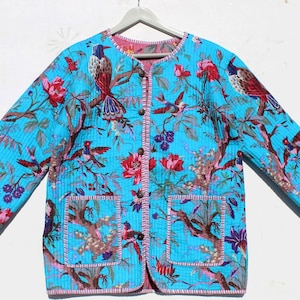 Könnte beinhalten: Eine türkisblaue gesteppte Jacke mit einem Blumendruck mit Vögeln und rosa Blüten. Die Jacke hat einen Knopfverschluss und zwei Taschen.