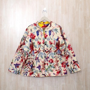 May include: A cream-colored quilted jacket with a floral print featuring red, blue, and green birds. The jacket has a mandarin collar and a button closure. The lining is a bright yellow color.