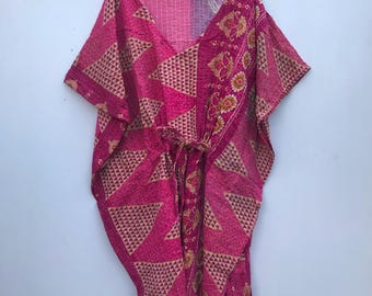 Puede incluir: Una kaftán de estampado rosa y dorado con cuello en V y mangas cortas. La kaftán tiene un lazo en la cintura.