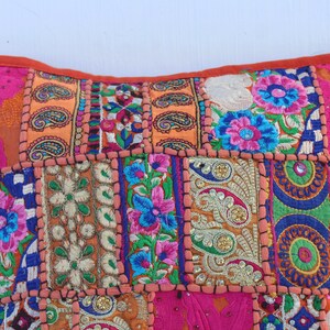 Puede incluir: Una almohada de patchwork colorida con bordados florales y lentejuelas. La almohada est&aacute; hecha de varias telas en tonos de rosa, naranja, azul, verde y dorado.