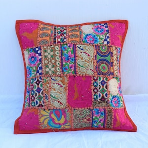Könnte beinhalten: Ein farbenfroher Patchwork-Kissenbezug mit rosa Hintergrund und aufwendigen Stickereien. Der Bezug besteht aus verschiedenen Stoffen und zeigt eine Vielzahl von Farben, darunter Orange, Blau, Grün und Gelb.