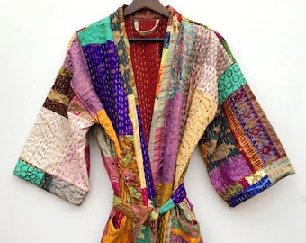 May include: A colorful patchwork robe with a long tie belt. The robe is made of various fabrics in shades of purple, pink, yellow, green, and brown. The fabric is stitched together in a patchwork design.