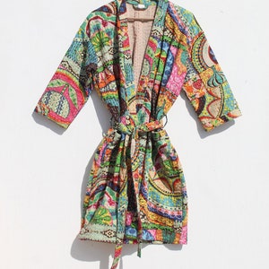 Könnte beinhalten: Eine farbenfrohe, gemusterte Robe mit einem Bindegürtel. Die Robe ist aus einem weichen, gesteppten Stoff gefertigt und zeigt eine Vielzahl von Farben und Mustern, darunter Paisley, Blumen und geometrische Muster.