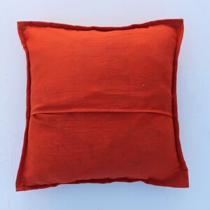 Puede incluir: Un coj&iacute;n de color naranja s&oacute;lido con un dise&ntilde;o simple. El coj&iacute;n est&aacute; hecho de una tela suave y texturizada.