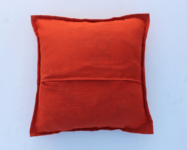 Puede incluir: Un coj&iacute;n de color naranja s&oacute;lido con un dise&ntilde;o simple. El coj&iacute;n est&aacute; hecho de una tela suave y texturizada.