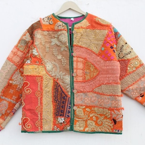 Könnte beinhalten: Eine Patchworkjacke aus einem Mix aus orangefarbenen, rosafarbenen und goldenen Stoffen. Die Jacke hat einen Knopfverschluss und lange Ärmel. Der Stoff ist mit Stickereien und Pailletten verziert.