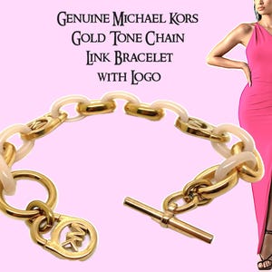 May include: Gold tone chain link bracelet with a white resin accent and a Michael Kors logo charm. The bracelet has a toggle clasp.