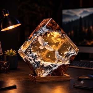 May include: A diamond-shaped resin and wood lamp featuring an internal winter scene with a white owl in flight and a howling wolf. The diorama includes snow-covered rocky terrain and pine trees, illuminated by a warm internal light source.