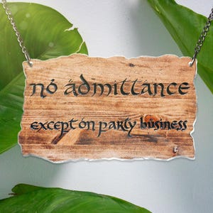 以下が含まれることがあります： 銀色のチェーンからぶら下がっている、素朴な仕上げのウッドサイン。サインには、黒いスタイリッシュなフォントで「No admittance except on party business」と書かれています。