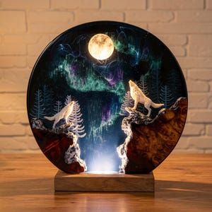 May include: A round decorative lamp featuring a nighttime forest scene with two white wolves howling at a full moon. The background depicts an aurora borealis with green and purple hues. The lamp is set on a wooden base.