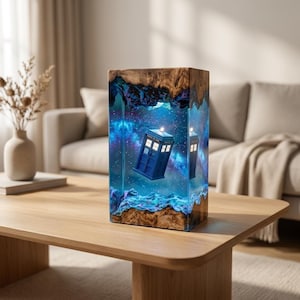 May include: A rectangular lamp featuring a blue police box encased in clear resin with a swirling blue and purple nebula design. The top and bottom sections are made of natural wood with a visible grain, creating a contrast with the resin.