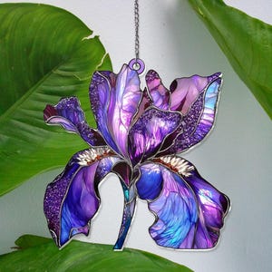May include: Purple and blue stained glass iris flower hanging ornament with a silver chain.
