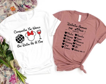 Peut inclure: Deux t-shirts blancs avec du texte noir et des graphiques. Le premier t-shirt dit "Conquering the World One Drink at a Time" et présente un globe terrestre, un nœud rouge et un verre de vin. Le deuxième t-shirt dit "Drinking Around the World: Checklist" et liste les pays avec une icône de tête de Mickey Mouse à côté de chacun.