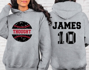 May include: Gray hooded sweatshirt with a black and white baseball graphic on the front. The graphic has red stitching and the word "THOUGHT" in red letters. The back of the sweatshirt has a black baseball graphic with the name "JAMES" and the number "10" in black.