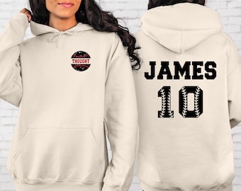 Puede incluir: Una sudadera con capucha blanca con un gráfico de béisbol en la parte delantera que dice "Thought" y un gráfico de béisbol con el nombre "James" y el número "10" en la parte posterior.