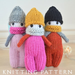 May include: Three hand-knitted dolls with hats and scarves in grey, yellow, and black. The dolls have pink, orange, and red bodies. The text "KNITTING PATTERN" is at the bottom of the image.