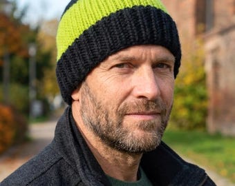May include: A knit beanie featuring a wide band of neon yellow yarn contrasted by a thick black ribbed brim and a black crown. The hat is constructed with a visible knit texture, showcasing a bold color-blocked design in black and bright yellow.