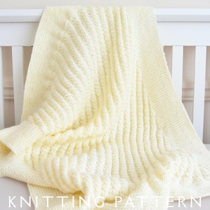 May include: A soft, cream-colored knitted blanket with a ribbed pattern. The blanket is draped over a white crib rail. The words "KNITTING PATTERN" are visible at the bottom of the image.