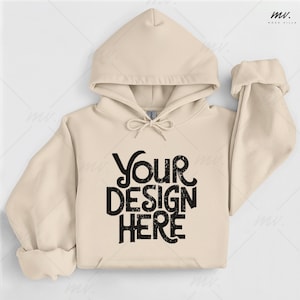 May include: Cream-colored hoodie with a drawstring hood and a front pocket. The text "Your Design Here" is printed in a distressed black font across the front. The sleeves are cuffed.