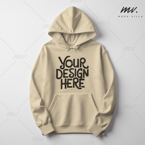 May include: A beige hoodie with a drawstring hood and a kangaroo pocket. The front of the hoodie features the text "YOUR DESIGN HERE" in a bold, black font. The hoodie is a neutral color, suitable for various design applications.