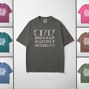 Può includere: Una collezione di t-shirt in vari colori, tra cui rosa, verde acqua e blu, ognuna con la scritta "Your Design Here". La maglietta centrale è grigia e presenta il testo "C1717 MOCKUP BUNDLE 40 COLORS."